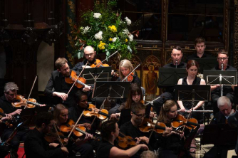 orchesta members playing the music in front of the christmas tree