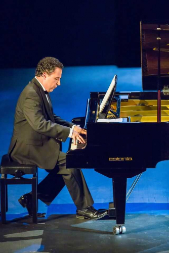 Michael Bulychev-Osker seated in profile, playing the piano