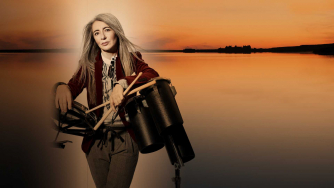 Evelyn Glennie holding percussion instruments in front of a Scottish loch