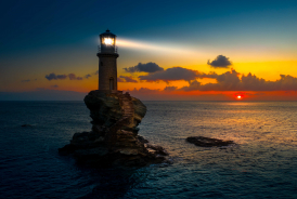 A lighthouse shining at sunset.