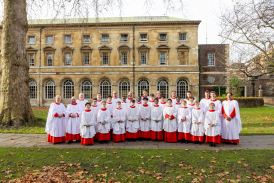 The Choir of Westminster Abbey standing in red cassocks and white surplices on grass